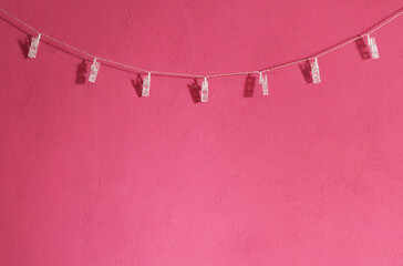 Plastic clothesline hanging over a pink / magenta wall. Copy space for additional content.  - obrazy, fototapety, plakaty