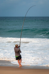 One solitary man bait fishing in the Indian Ocean on a warm winter day when the sun is setting. Cape Vidal beach, KwaZulu-Natal - South Africa 
