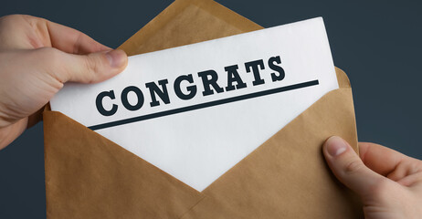 Male hands holding craft envelope with word CONGRATS on blue background