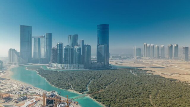Buildings on Al Reem island in Abu Dhabi timelapse from above. Aerial citiscape of Al Reem Island, showing the reflection of buildings in the water and shadows with fog
