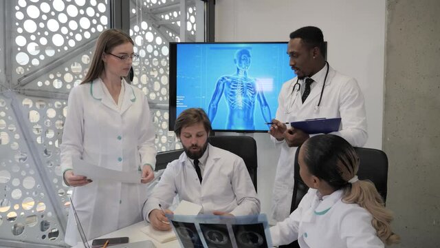 Conference of four multiethnic doctors in a modern high-tech heart failure clinic.