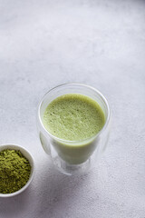 Matcha with milk in a glass on a light background