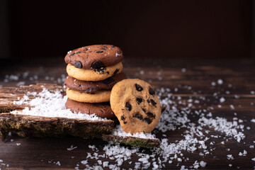 Chocolate chip cookie tower on a dark wooden background with snow.