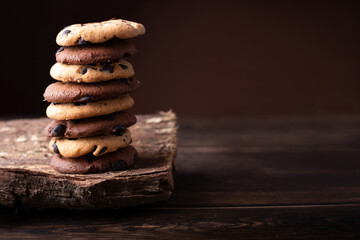 Tall сhocolate chip cookie tower on a dark wooden background.