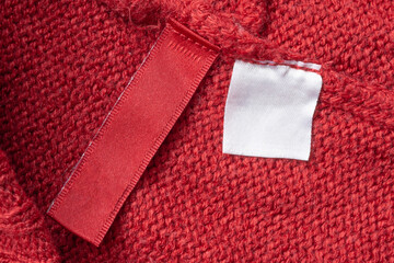 Blank laundry care clothes label on red knitted fabric texture background