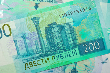 Naklejka premium Russian banknotes of 200 rubles. Tinted background. Unusual catchy backdrop or wallpaper on the theme of the Russian economy. Light blue and aquamarine colors. View from above. Close-up