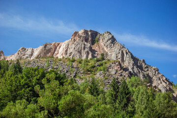 View of the mountain peak below the forest. Romanian mountain near Bicaz Gorge. Carpathian mountains rare massive and pine forest landscape Romanian countryside in summer sunny day