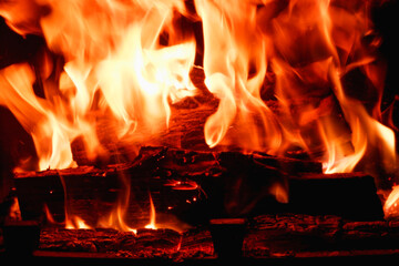 Abstract fire flame in fireplace, texture for background. Beautiful bright orange flames flicker in the darkness of the night.