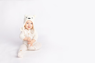 baby in a warm suit and a bear hat on a white isolated background, space for text