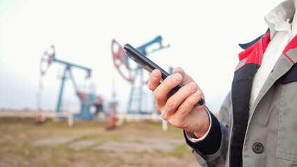 Closeup of a man's hand in uniform against the background of oil pumping, copy space
