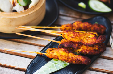 Chicken satay pieces on wooden skewers on a plate