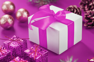 Christmas toys and a gift in a white box on a pink background.