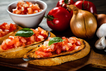 Bruschetta with ingredients on cutting board on wooden background
