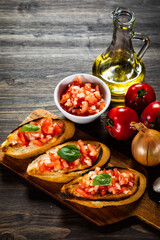 Bruschetta with ingredients on cutting board on wooden background
