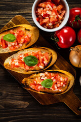 Bruschetta with ingredients on cutting board on wooden background
