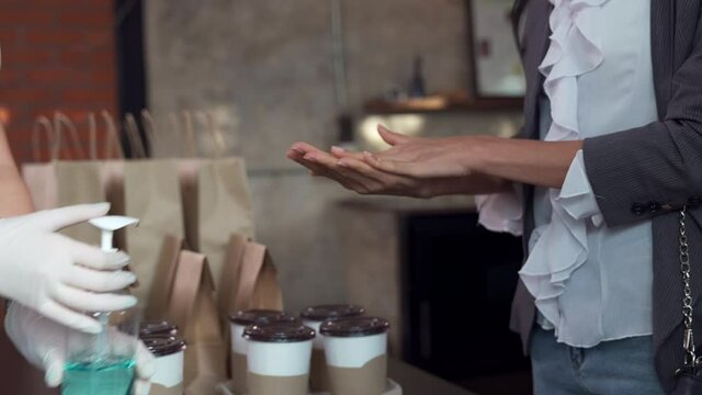 Customer Cleaning Hand With Hand Sanitizer Before Pick Up Take Out Coffee, 4K Slow Motion Handheld Tilt Close Up.