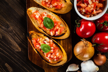 Bruschetta with ingredients on cutting board on wooden background
