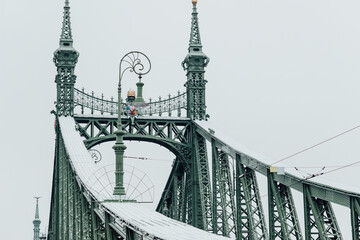 Famous Liberty bridge in Budapest, Hungary, details of architecture, towers and street lamps during cloudy winter day