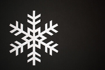 One paper cut snowflake on black background