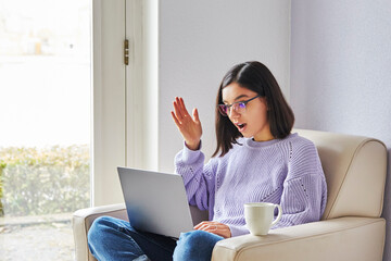 surprised young ethnicity woman with glasses looking in computer a. Lockdown news, online shopping...