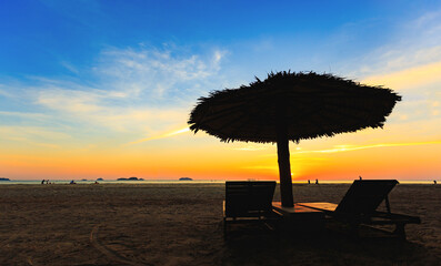Sunbeds, sun loungers, umbrellas under palm trees White sandy beaches, sea views with horizon, colorful night sky, calm. Beautiful sunset scenery Silhouette style © photosky99