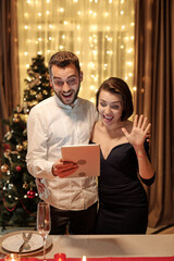 Young cheerful elegant couple waving hand and communicating in video chat