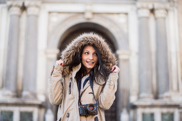 Pretty woman in a fur coat poses in Granada town hall square while sightseeing