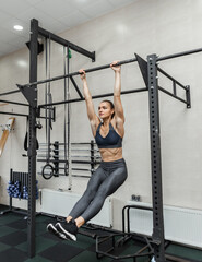 Functional training. Young fit woman working out on the horizontal bar in the gym