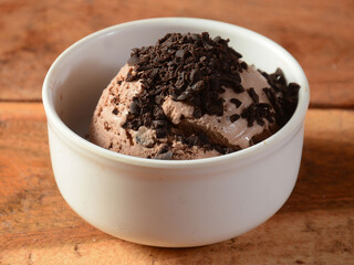 Choco chips ice cream scoop served in a bowl over a rustic wooden table, selective focus