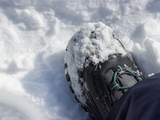 Single trekking boot on crushed pure snow. Winter time background concepts. Top view