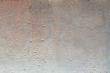 Natural frozen drops of condensation on transparent glass. Beautiful background from a frozen window in winter. Drops texture on the glass