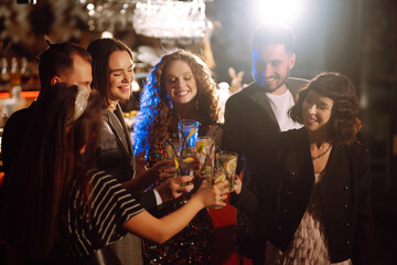 Group of friends cheering and drinking cocktails together at the bar. Young people celebrating winter holiday together with coctails at a nightclub party. Youth, lifestyle, drink, birthday concept.
