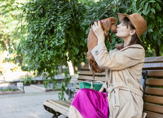 Fototapeta premium Cute dachshund puppy sitting in the arms of the hostess outdoors