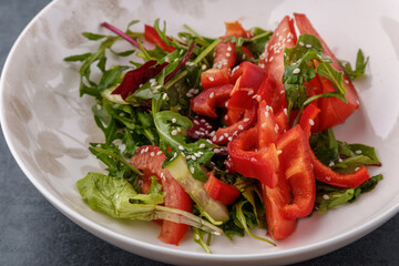 Vegan Spring Salad. Tomato, lettuce, dressing, bell peppers and avocados. Fork with vegetables and salad.