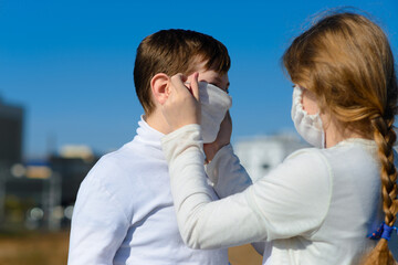 Little sister and brother in casual clothes, protective masks ready for school