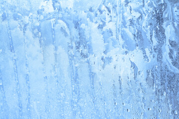 Natural frozen drops of condensation on transparent glass. Beautiful background from a frozen window in winter. Drops texture on the glass