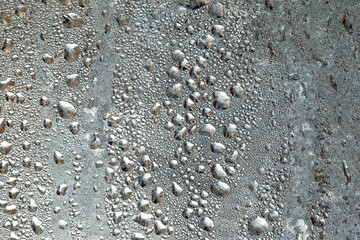 Natural frozen drops of condensation on transparent glass. Beautiful background from a frozen window in winter. Drops texture on the glass