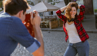 Guy takes pictures of a happy attractive girl in the city