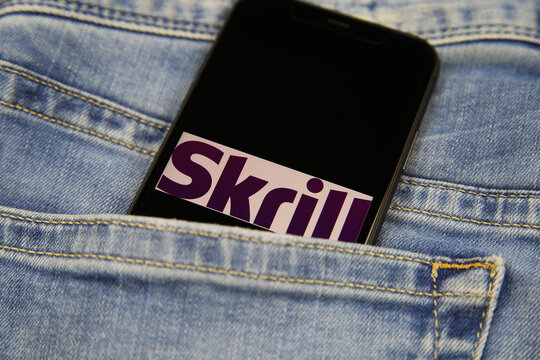 Viersen, Germany - May 9. 2020: Close up of two isolated mobile phones with payment provider Skrill logo lettering in jeans pocket