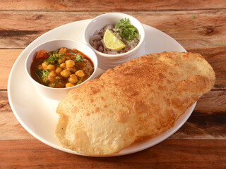 Chole Bhature, spicy Chick Peas curry also known as Chole or Channa Masala is traditional North Indian main course recipe and usually served with fried puri or Bhature, selective focus - obrazy, fototapety, plakaty