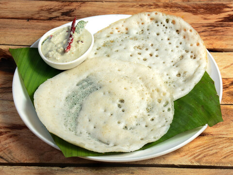 Kerala traditional breakfast food Appam or Kallappam or Vellappam served with chutney over a rustic wooden background, selective focus