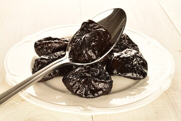 Sweet organic prunes, close-up, on a wooden table.