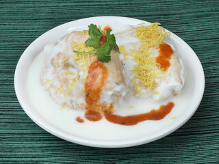 Dahi Vada or Bhalla is a popular snack in India. It is prepared by soaking vadas in thick dahi curd. Garnished with coriander leaves, grated carrots and kara boondi, selective focus