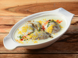 Dahi Vada or Bhalla is a popular snack in India. It is prepared by soaking vadas in thick dahi curd. Garnished with coriander leaves, grated carrots and kara boondi, selective focus