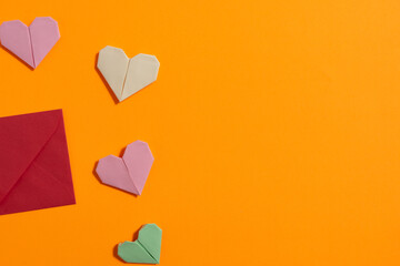 Origami hearts made with colored paper for congratulations on Valentine's Day for couples in love, on yellow background