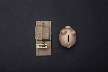 Mousetrap with loan bait and piggy bank on black background. Trap, risks or deception concept