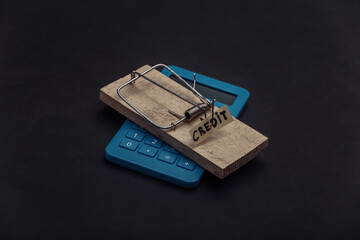 Mousetrap with loan bait and calculator on black background. Trap, risks or deception concept