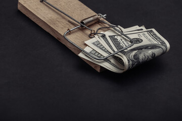 Mousetrap with dollar bait on black background. Trap or deception concept