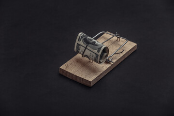 Mousetrap with one hundred dollar bill on black background