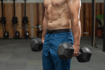 Muscular man holding heavy dumbbells in the gym